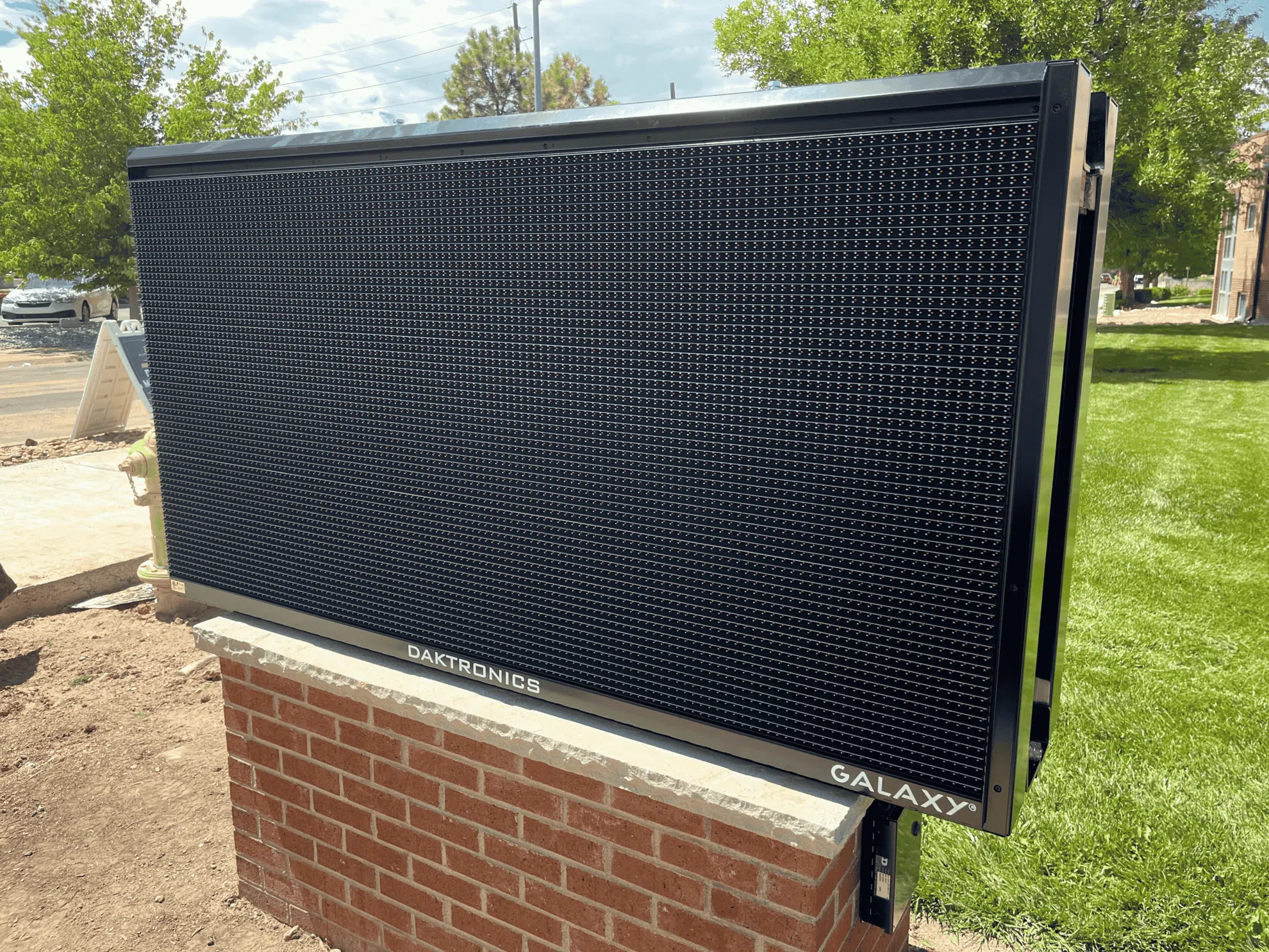 Outdoor digital sign with bright LED display promoting a business, photographed in daylight