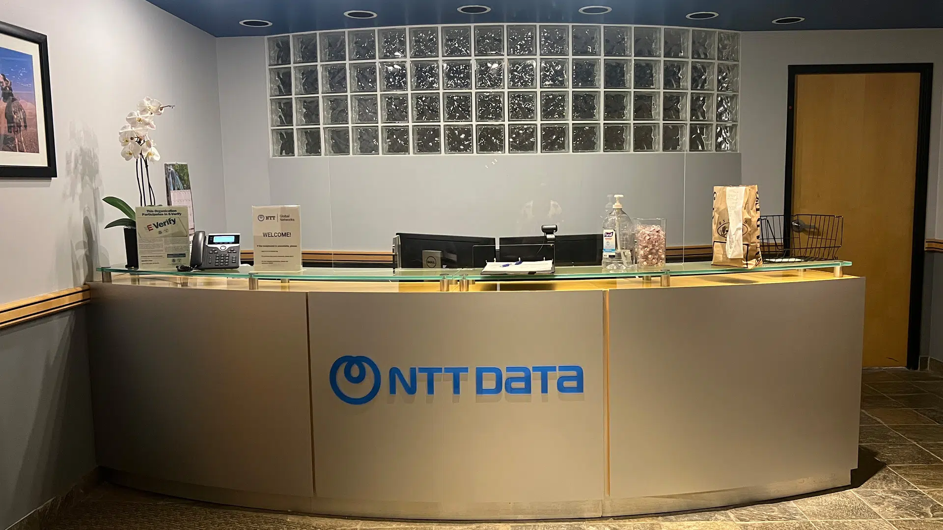 A custom-made, backlit lobby sign featuring a company logo in a modern Denver corporate office reception area.