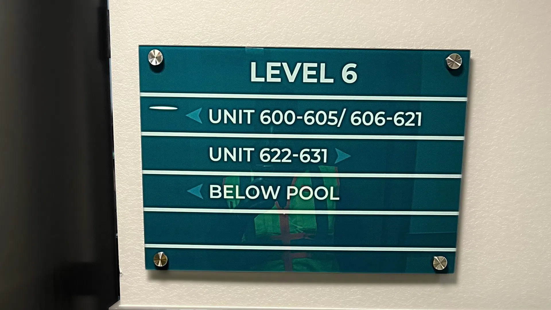 A modern, clear directional wayfinding sign installed in a Denver corporate office building