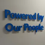 Dimensional blue wall lettering in a Denver corporate office reading ‘Powered by Our People,’ showcasing modern workplace branding