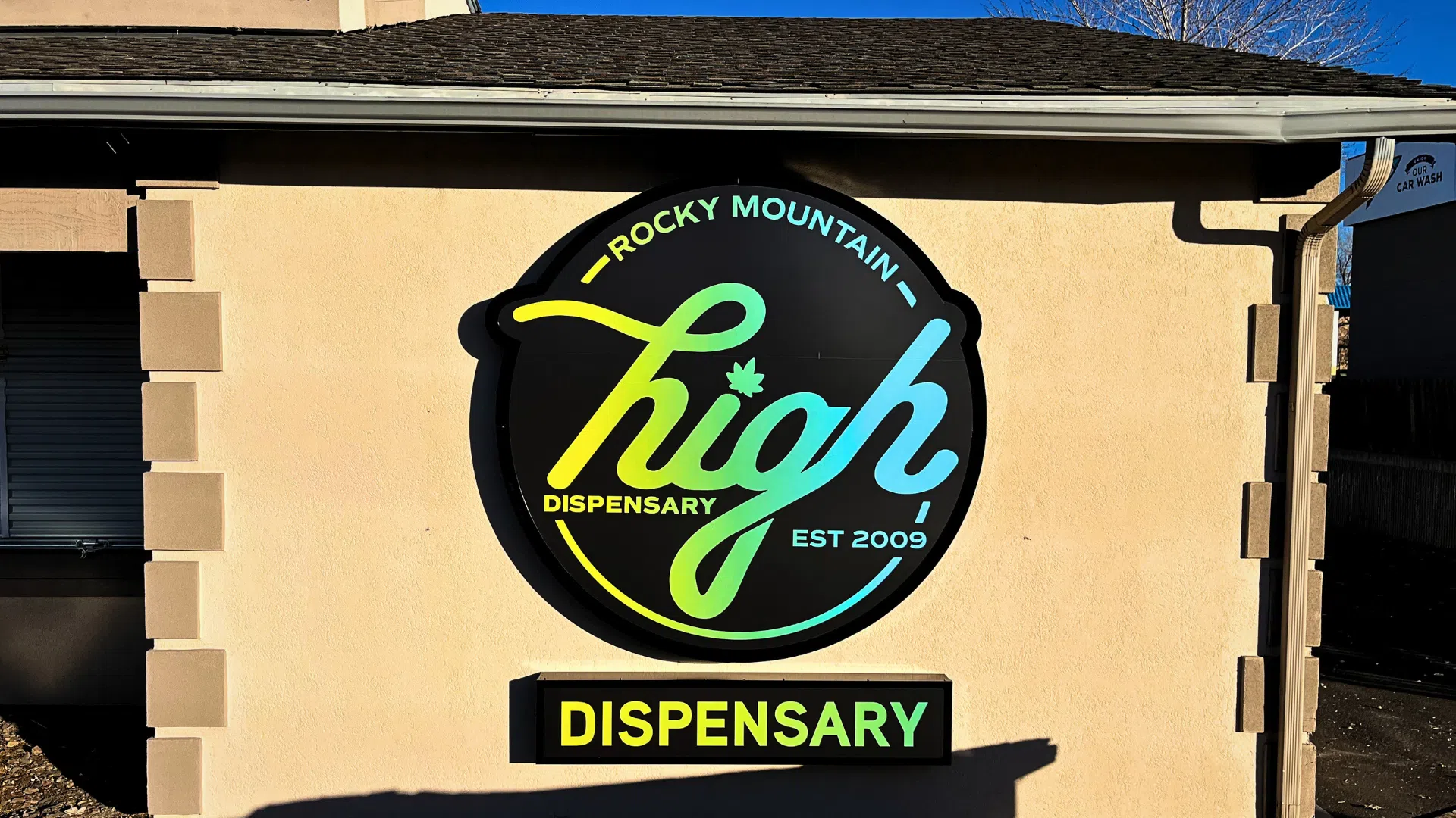 Illuminated exterior wall sign for Rocky Mountain High Dispensary mounted on a commercial building facade.