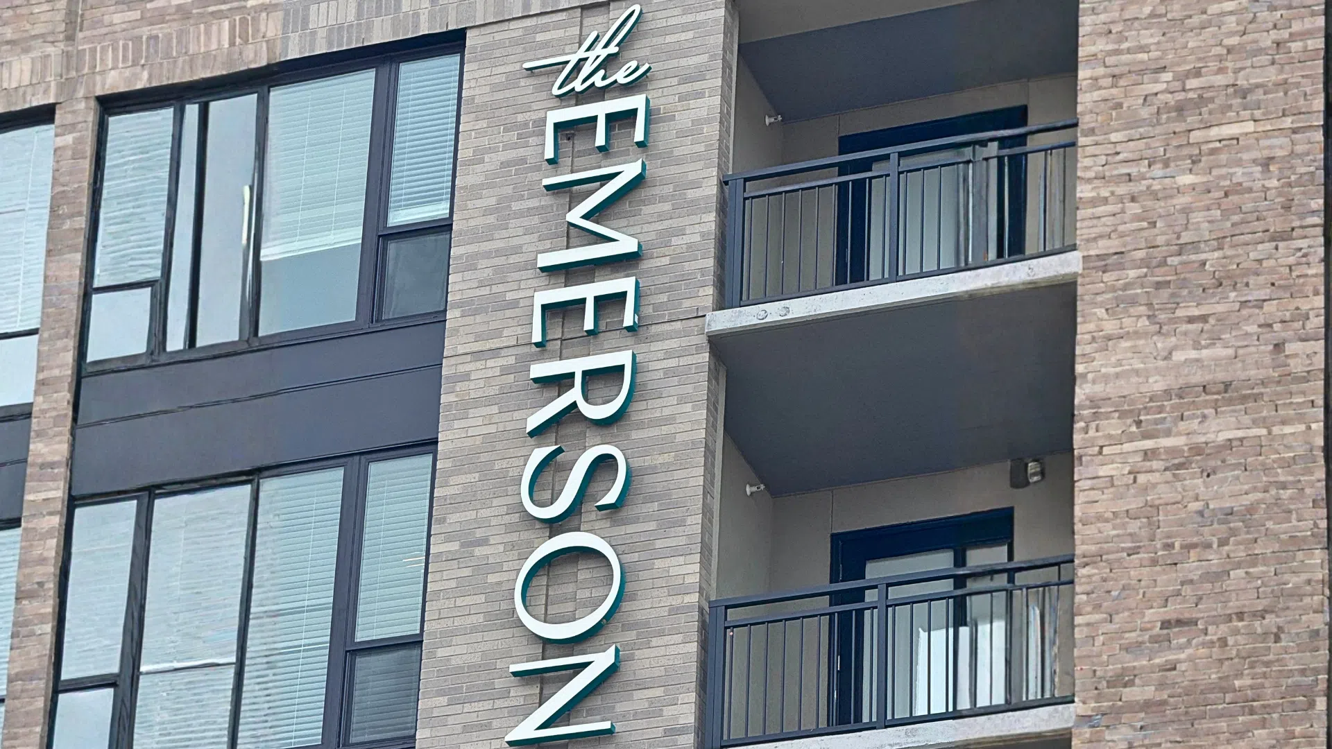 Vertical channel letter sign for The Emerson apartment building mounted on a modern brick exterior facade.