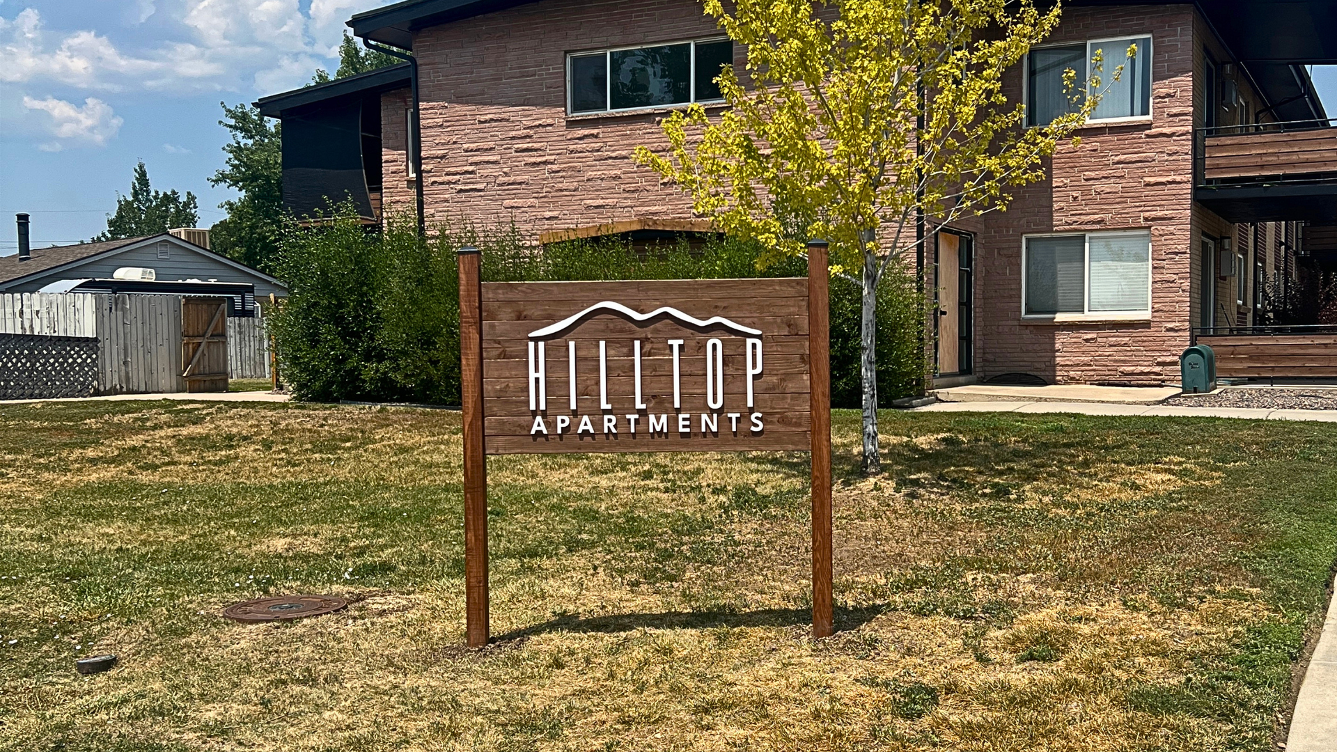 Custom wood post and panel apartment monument sign installed outside a multifamily property in Denver, Colorado, helping improve property visibility and attract prospective tenants.