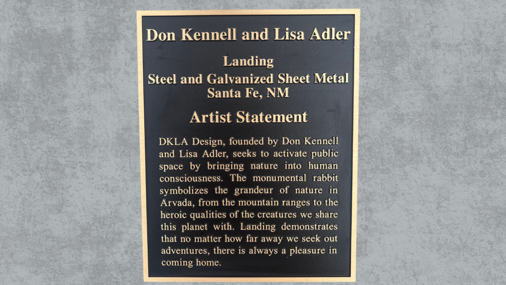 Custom bronze metal plaque with raised lettering and gold border mounted on a concrete wall