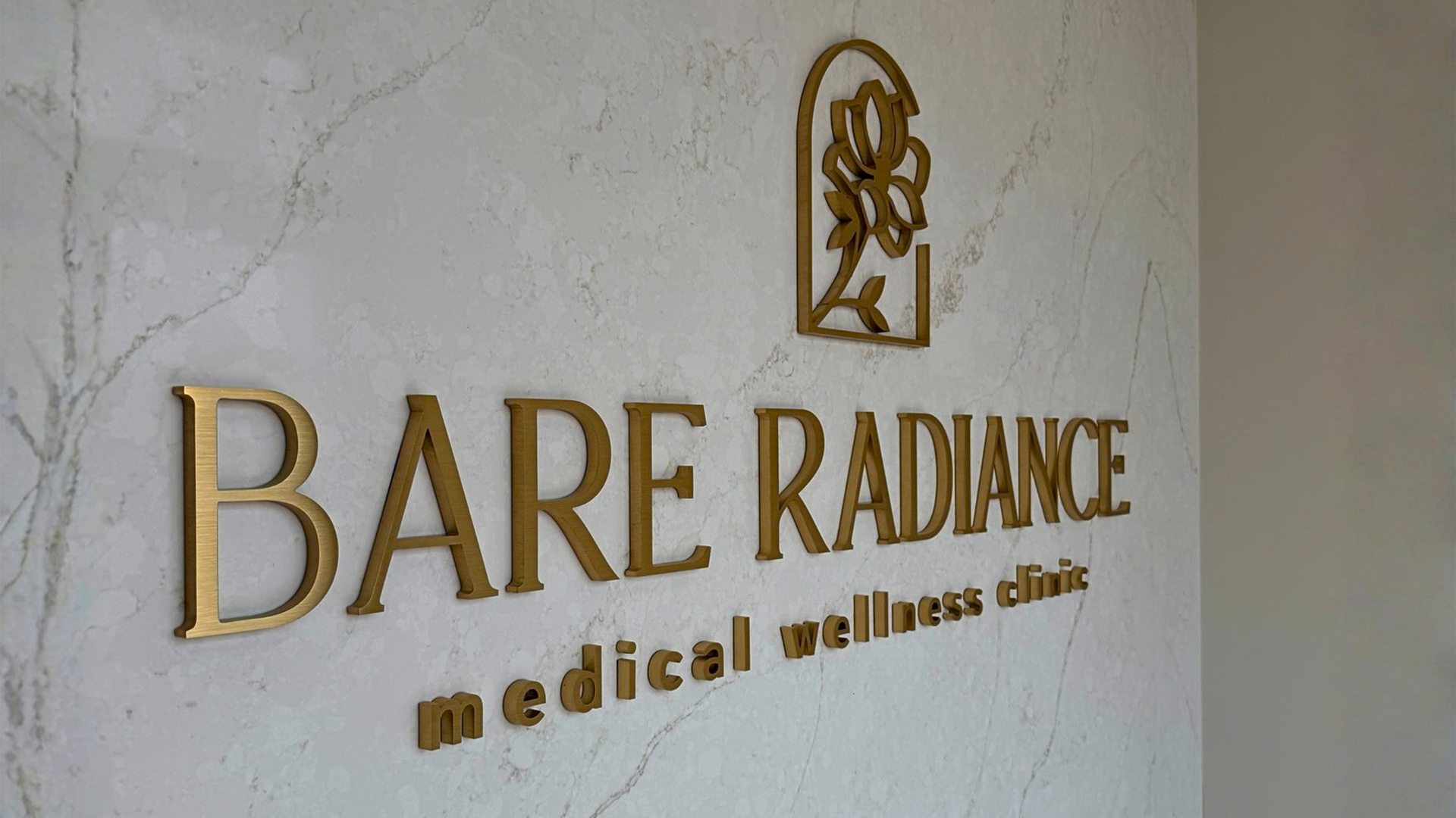 Custom brushed gold dimensional letter sign installed inside a Denver medical wellness clinic, showcasing professional commercial interior signage.