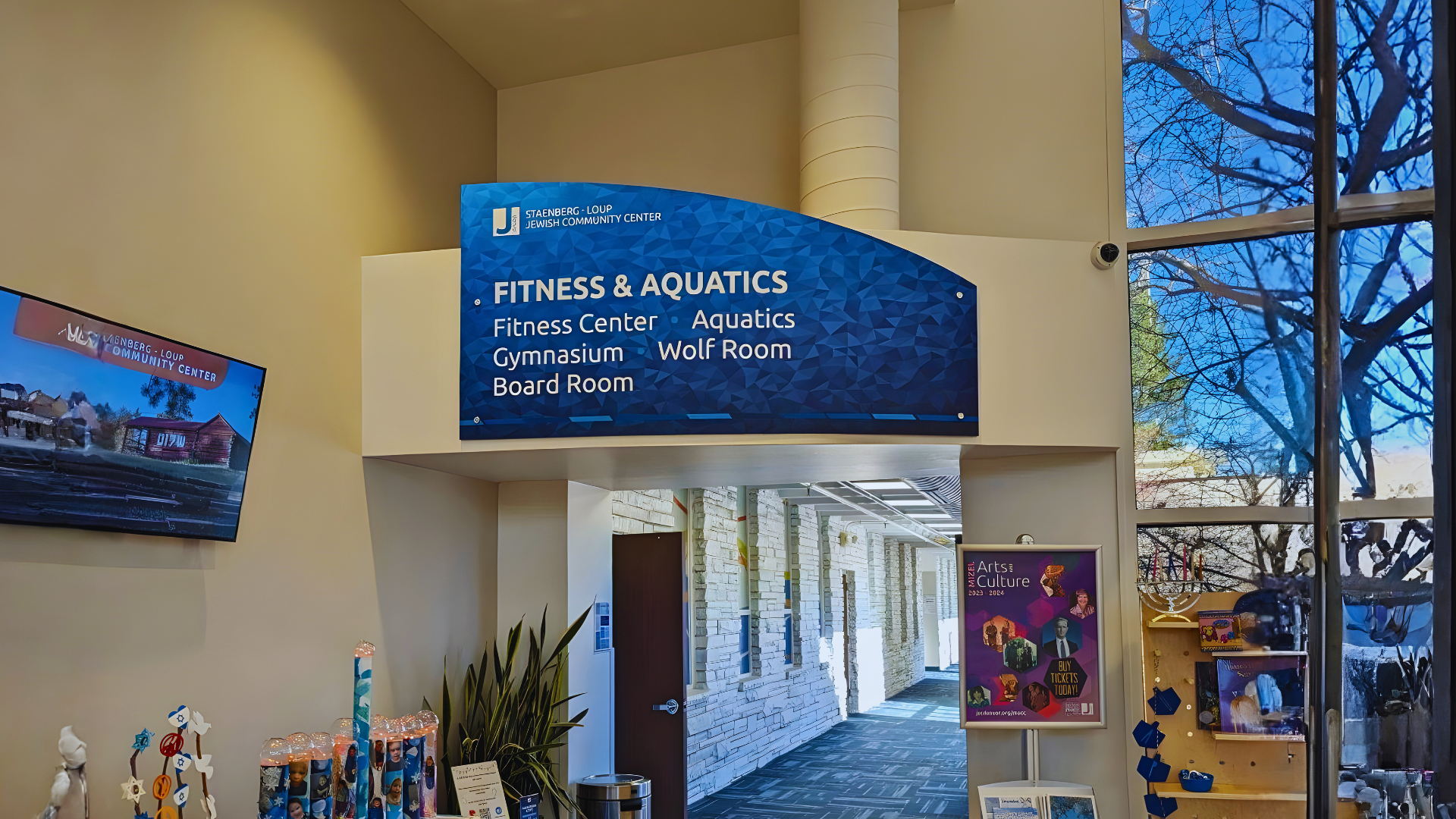 Interior wayfinding sign directing visitors to the fitness center, aquatics, gymnasium, board room, and other areas of a community center.