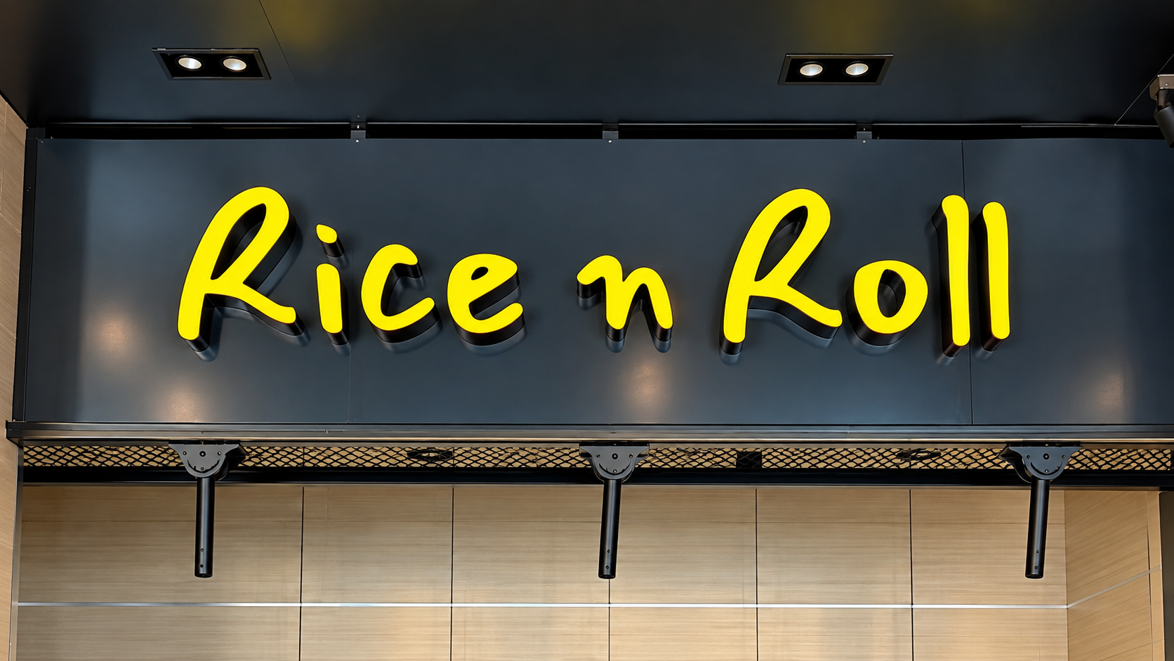Yellow dimensional Rice n Roll restaurant sign mounted on a dark interior wall